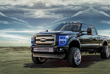 Black off-road truck with LED bar lights and halo headlights on a sandy beach